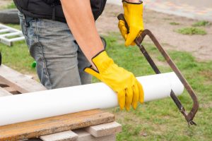 Worker cutting gutter pipe for Eugene Gutter Service