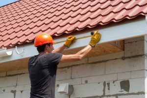 Worker measuring and installing new gutters.